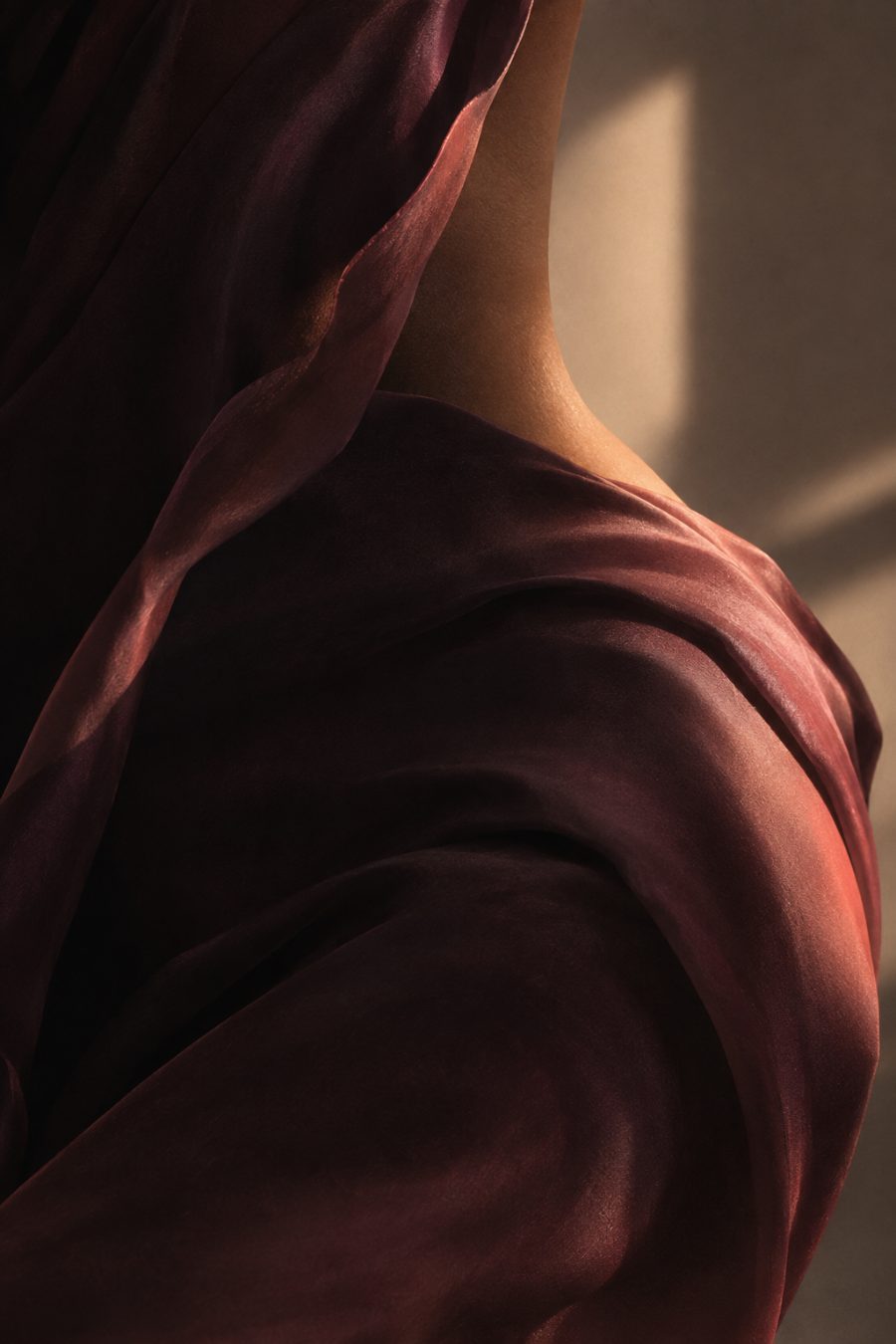 Close-up of a shoulder draped in plum silk in soft window light